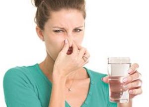 Woman rotten egg smell glass of water